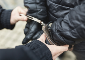 Close up of hands attaching handcuffes to gloved hands