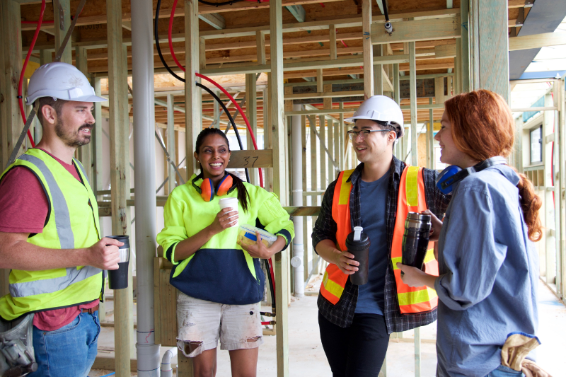 Group-of-smiling-staff-some-in-hard-hats-on-building-site