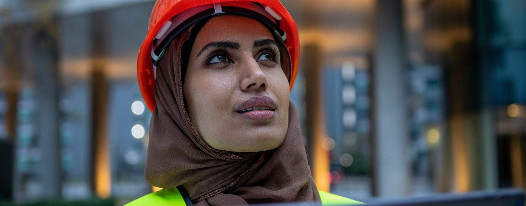 UK, London, Female engineer in hijab and hardhat using digital tablet